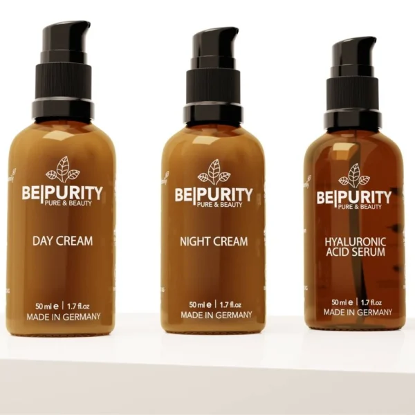 Drei braune Flaschen mit schwarzen Pumpen stehen auf einer weißen Oberfläche, mit der Aufschrift „BePurity Pure & Beauty“ und „Made in Germany“. Dieses BePurity Feuchtigkeits-Trio-Set enthält Tagescreme, Nachtcreme und Hyaluronsäure-Serum. Jede Flasche enthält 50 ml (1,7 fl oz) Produkt, um Ihre Haut strahlend und hydratisiert zu halten.
